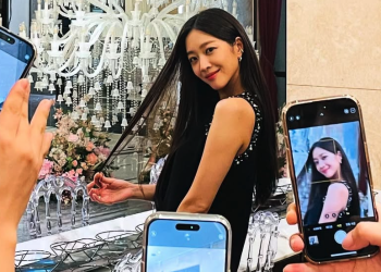 화려한 샹들리에 앞에서 머리를 쓸어 넘기며 미소 짓는 조보아를 여러 대의 휴대폰 카메라가 촬영하는 장면