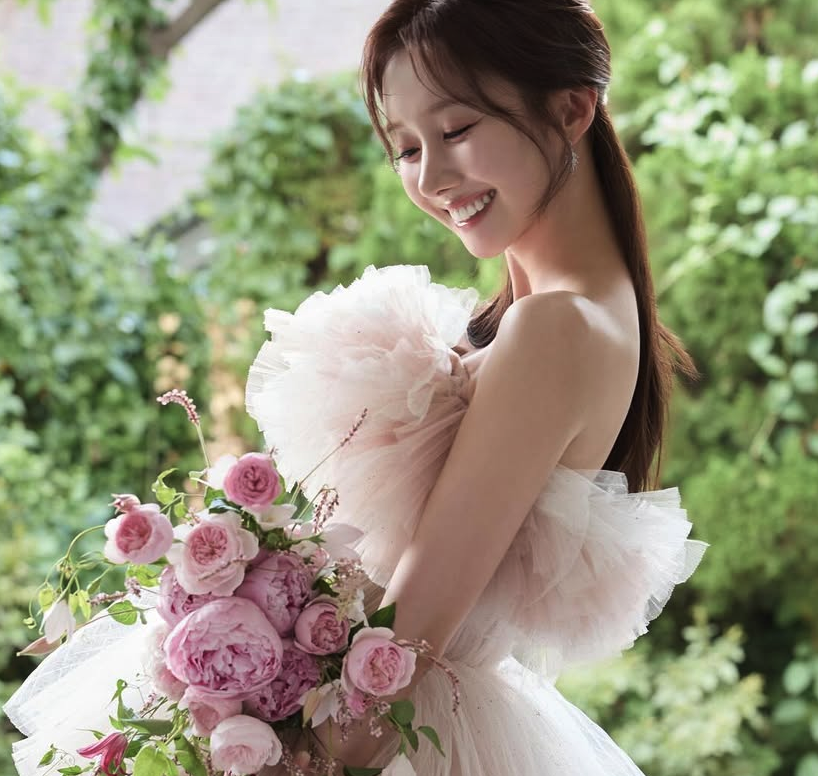 윤수빈 아나운서가 웨딩드레스를 입고 꽃다발을 들고 미소 짓는 모습