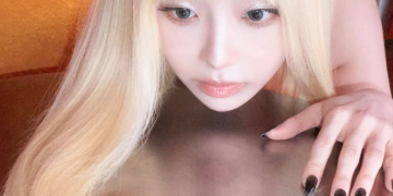 긴 금발 머리를 늘어뜨린 채 반사되는 금속판 위에 턱을 괴고 신비로운 표정으로 정면을 응시하고 있는 가수 츄의 모습
