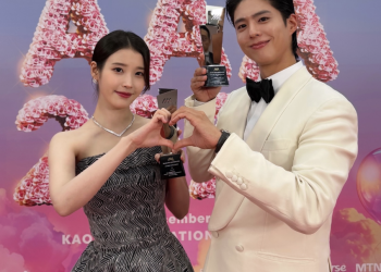 2025 아시아 아티스트 어워즈(AAA) 레드카펫 배경 앞에서 트로피를 들고 손하트를 만들고 있는 박보검과 아이유의 다정한 모습