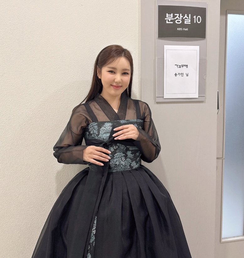 KBS 가요무대 분장실 10호 앞 복도에서 검은색 시스루 한복을 입고 손을 가지런히 모은 채 미소 짓고 있는 가수 송가인의 모습
