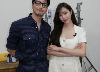 티파니 영과 변요한이 팔짱을 끼고 나란히 서서 카메라를 응시하는 모습. 변요한은 안경과 줄무늬 셔츠를, 티파니는 흰색 반팔 원피스를 착용하고 있다.
